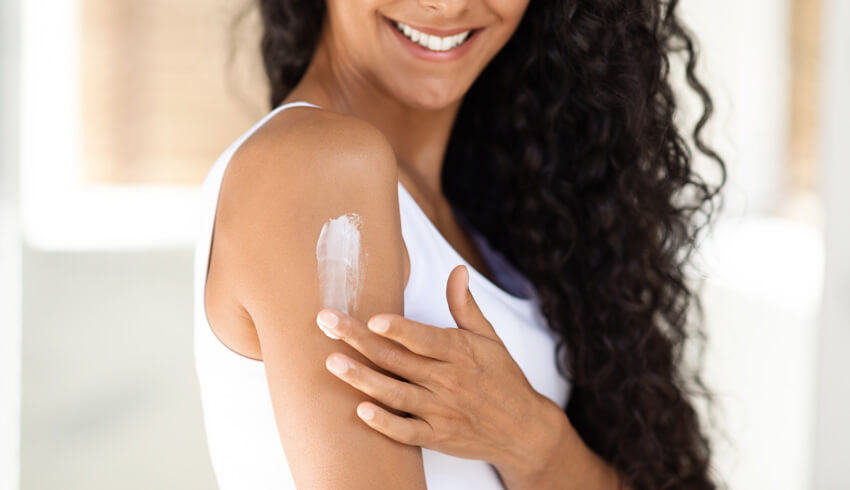Woman applying cream onto her arm