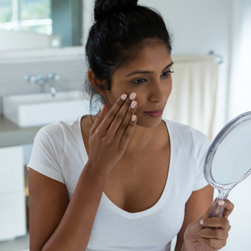 Latino woman examining her skin