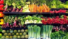 A display of grocery store produce shelves stocked with fresh vegetables. 