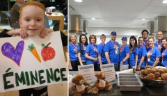 A young boy holding a hand drawn picture of a heart, a carrot and apple with Eminence written below and the Eminence Organics team posing for a picture at a Soup Night.