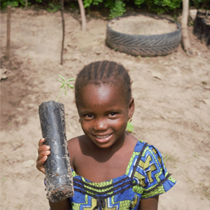 A young girl holds a seedling to be planted as part of the Forest for the Future Initiative to grow sustainable Forest Garden Projects in Koungheul, Senegal. 