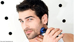 A man using an electric razor to shave along his jaw line. 
