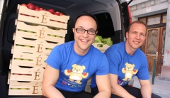 Eminence Organic President Boldijare Koronczay and General Manager Attila Koronczay seated in the back of the van filled with donations of organic fruit in wooden crates.