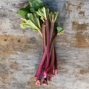 Stalks of rhubarb arranged on a wooden background. 