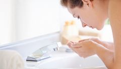 Woman washing face in sink