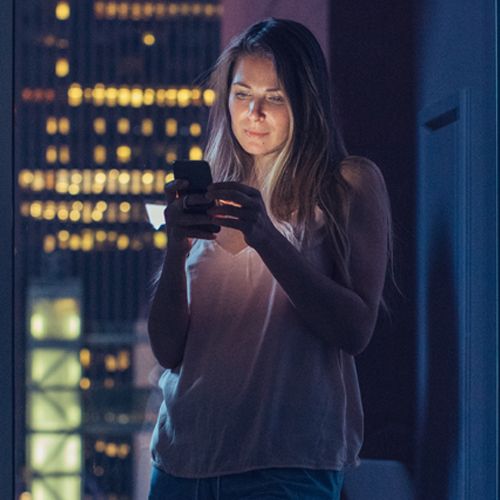 Woman at night looking at phone with blue light