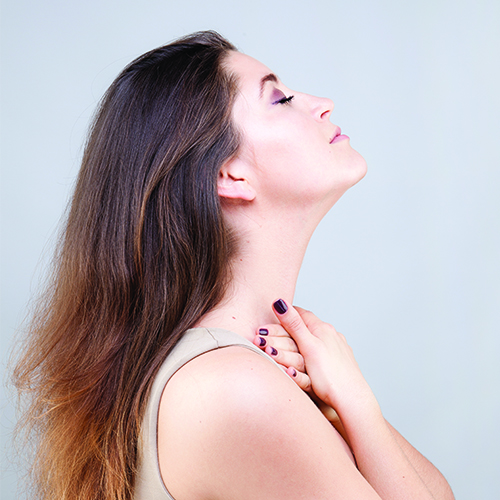 Woman stretching neck and using fingertips to massage the base of neck
