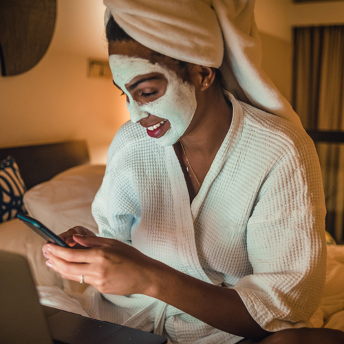 woman in overnight face mask in bed looking at phone