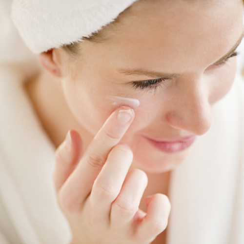 Woman applying moisturizer onto face