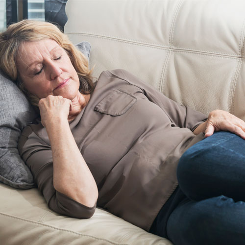 mature woman falling asleep on the couch