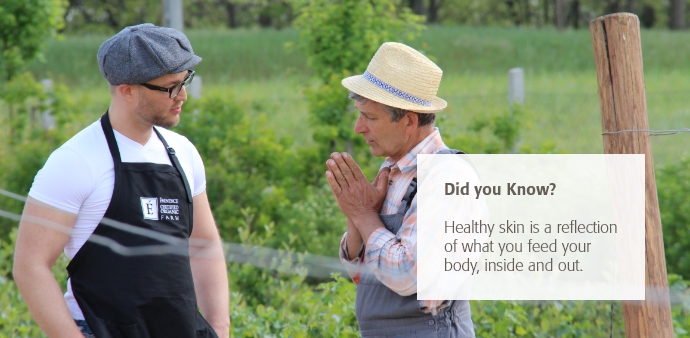 A farm caretaker and Eminence Organic Skin Care President Boldijarre Koronczay having a conversation in a field of green vegetation. 